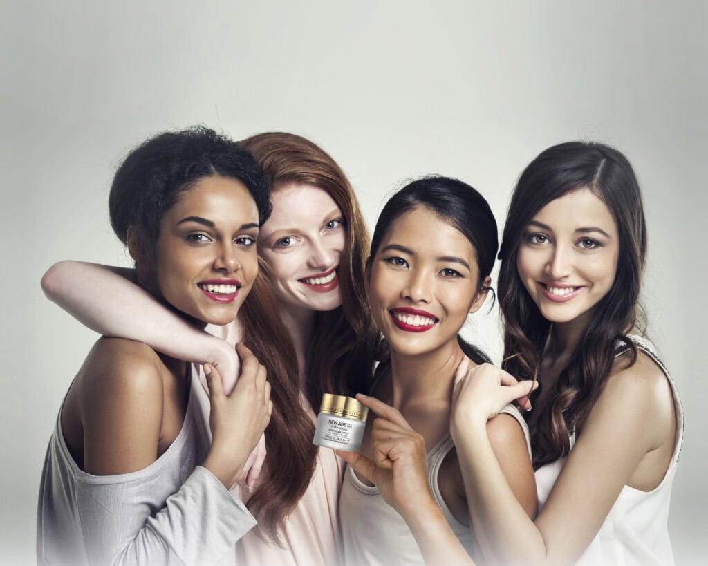 Group of four smiling young women with healthy skin posing together, showing natural beauty and confidence.