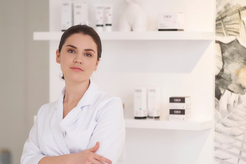 Professional beauty therapist in GIGI training facility with skincare products for international certification courses